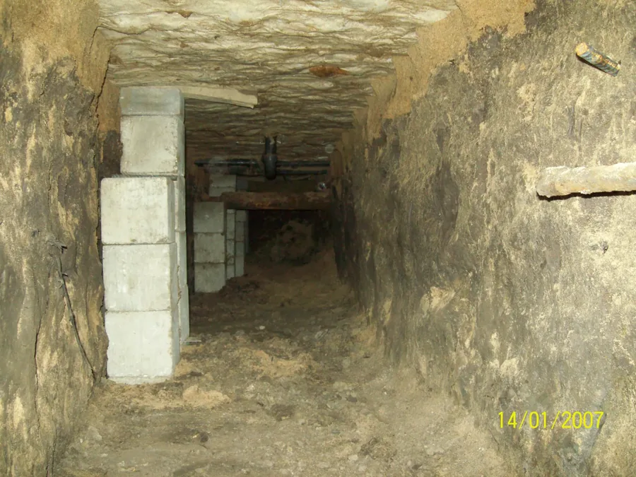 Excavated access tunnel and block piers beneath a home being prepared for lifting