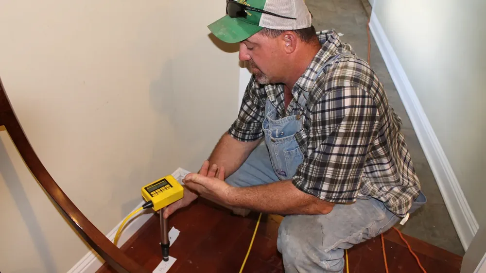 Technician measuring floor elevation with a precision ZipLevel gauge during a foundation survey