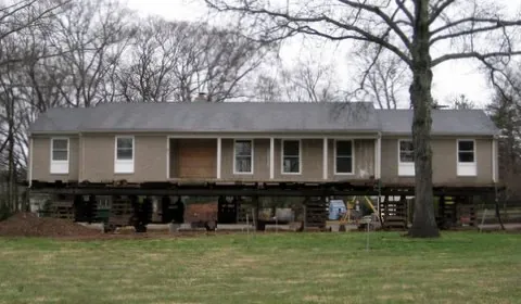 Home held on engineered cribbing while a new elevated foundation is built beneath it